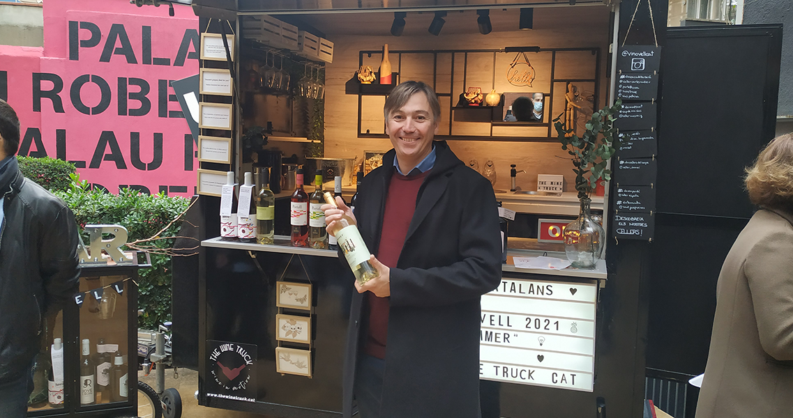 Marc Massana, responsable de la bodega, con la botella de vino Novell 2021 delante de la barra de vinos itinerante. 